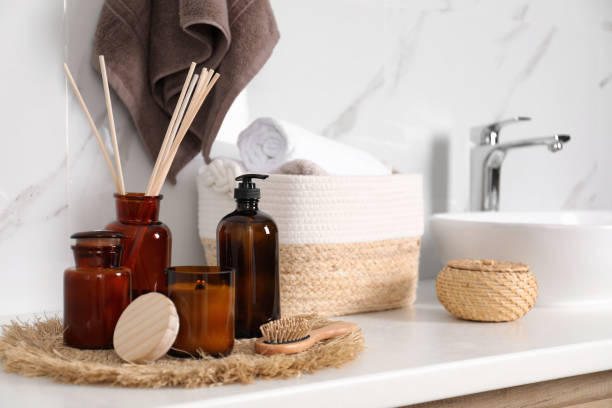 Soap dispenser, air reed freshener and burning candle on countertop in bathroom